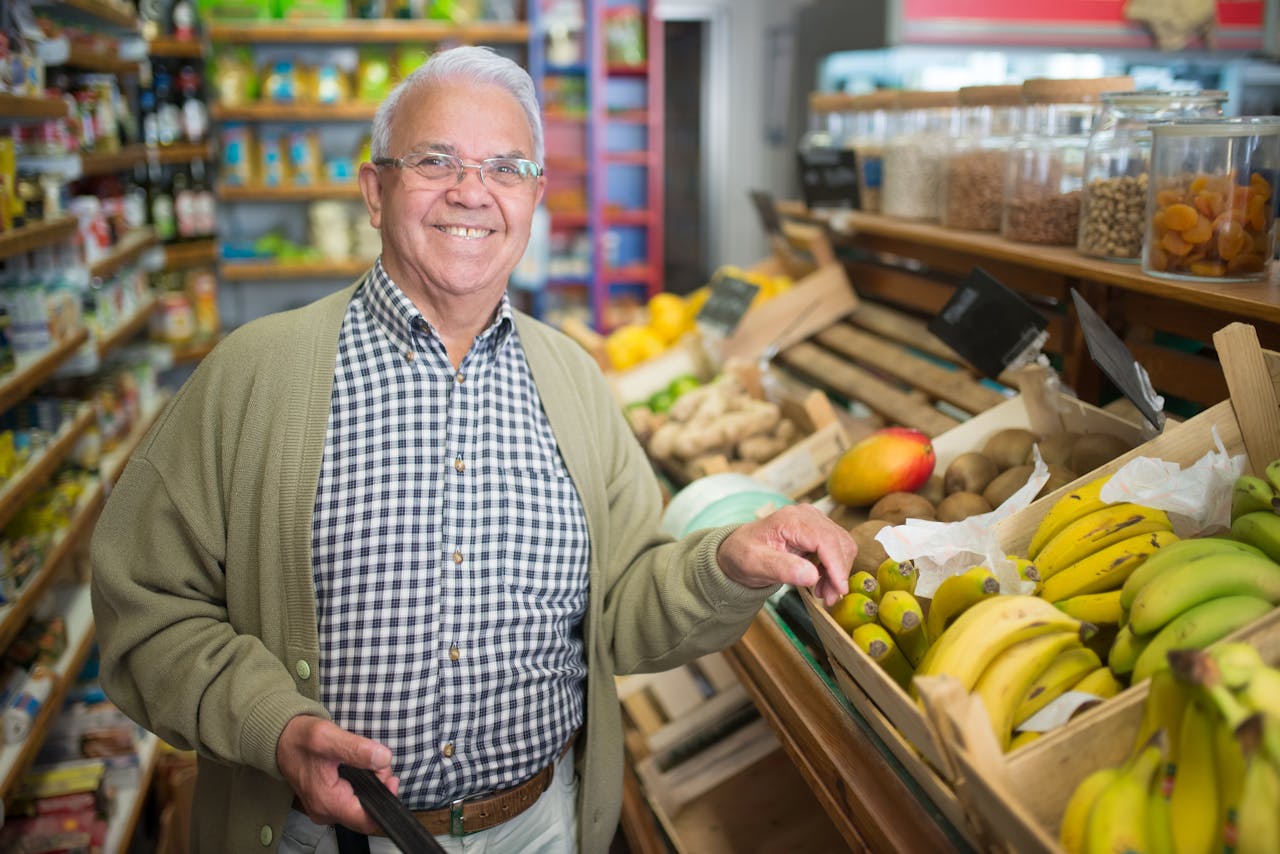 Senior man smiling while selecting fresh fruits in a grocery store.